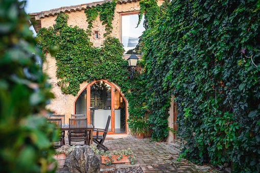 Green courtyard in house in Spain with table, chairs and greenery.