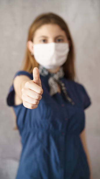 istock Young woman showing thumb up with face protective mask 1251126795
