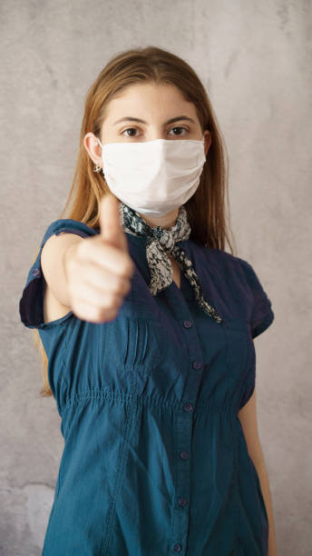 istock Young woman showing thumb up with face protective mask 1251126800