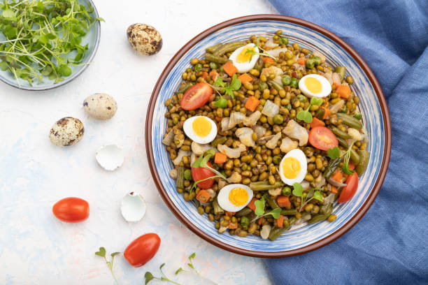 istock Mung bean porridge with quail eggs, tomatoes and microgreen sprouts on a white concrete background and blue textile. Top view, flat lay, close up. 1251127010