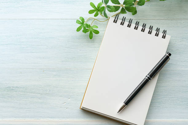istock Notebook and pen on wooden background 1251127065