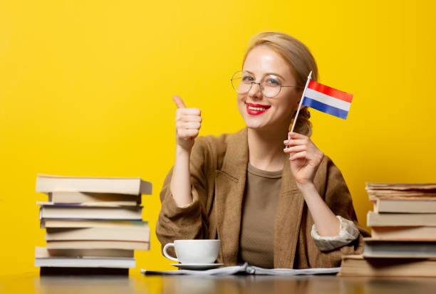 blonde woman with flag of Netherlands and books on yellow background stock photo