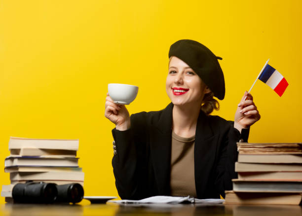 Style blonde woman in beret with French flag and books around on yellow background stock photo