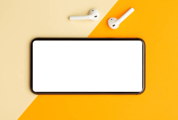 istock Flat lay, top view of orange office table desk with smartphone blank screen mockup with clipping path and wireless earphones. Modern working space 1251133749