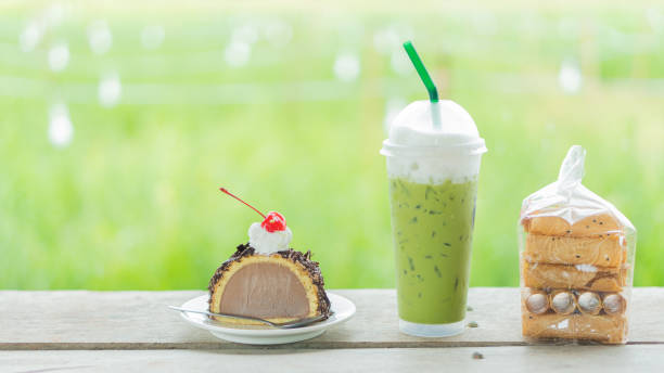 A cup of green tea on the table with cakes and desserts beside a blurred background