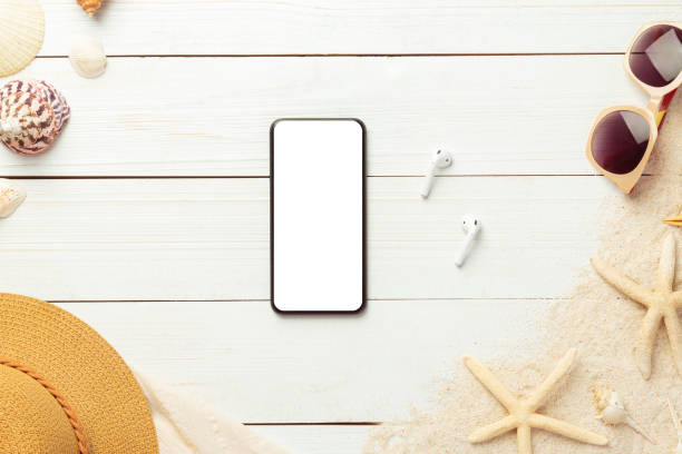 istock Summer background with blank screen phone and beach accessories - straw hat, sunglasses on white wood table background top view with copy space 1251134424