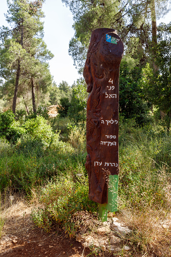 Jerusalem, Israel, June 13, 2020 : A standing wooden pillar with various figures carved on it and with inscription in Hebrew - 4 images of God in the Totem park in the forest near the villages of Har Adar and Abu Ghosh