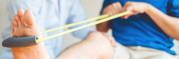 физиотерапевт человек дает сопротивление группы осуществлять лечение о колене спортсмена мужского пациента физическая терапия концепции - human knee pain human spine human joint стоковые фото и изображения