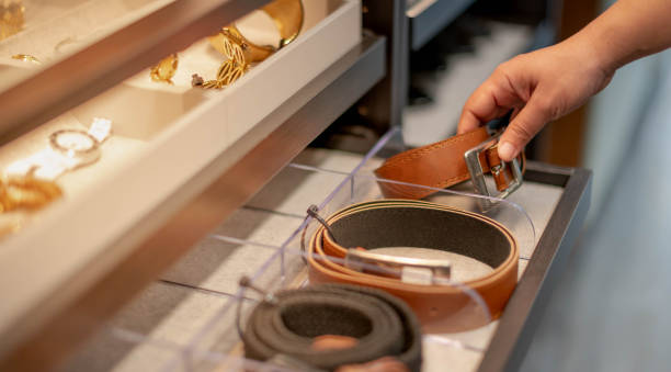 Female hand choosing the roll leather belt in the drawer shelf for the decision to buy stock photo
