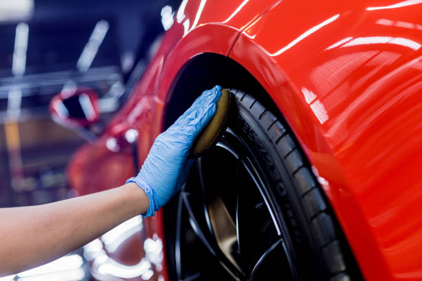 car service worker polishing car wheels with microfiber cloth. - polishing car imagens e fotografias de stock