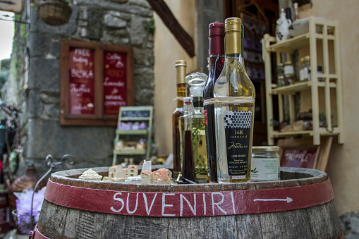 Hum, Central Istria, Croatia, Apr 19, 2018: Bottles of domestic liqueurs displayed on a wooden barrel in front of a souvenir shop on the town square.