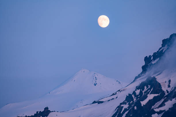 istock Golden full moon rising over distant mountains in the blue hour 1251139113