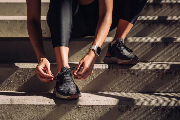 unrecognizable sportswoman tying laces on running sneakers, a close up - determination running staircase jogging imagens e fotografias de stock