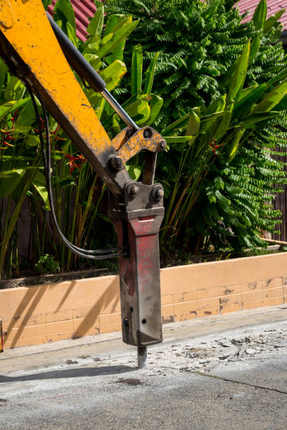 escavadeira quebrando e perfurando a estrada de concreto para reparo. grande martelo pneumático montado no braço hidráulico de um equipamento de construção. veículos de construção consertando estrada.martelo perfurado - 11902 - fotografias e filmes do acervo