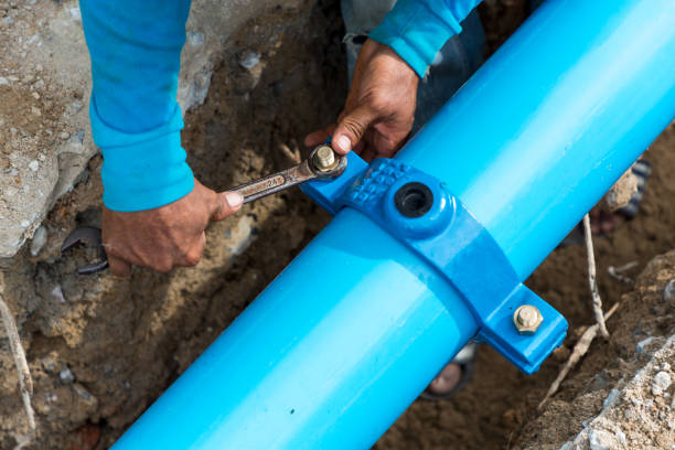 mann mit einem großen schraubenschlüssel auf wasserleitungen. baustelle mit neuen wasserleitungen im boden. kanalrohre zu reparieren oder in der straßenstadt zu reparieren oder zu restaurieren. - rohr stock-fotos und bilder