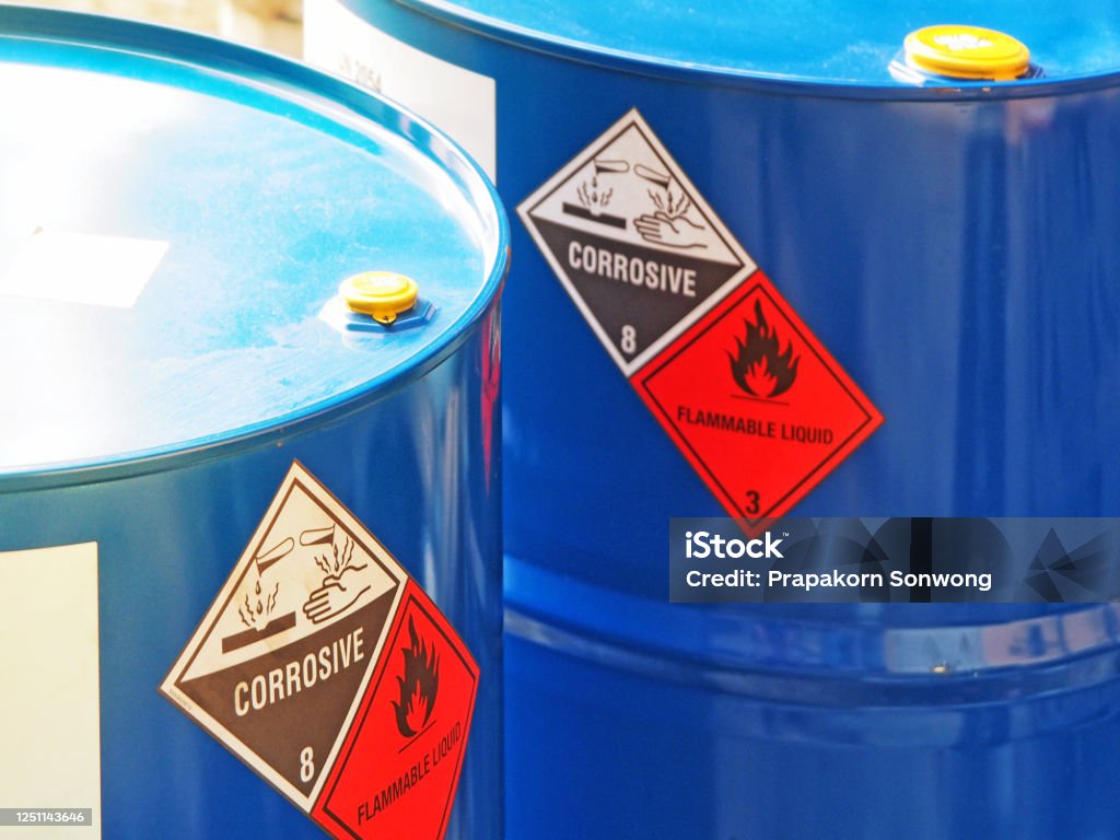 the close-up shot of blue color hazardous dangerous chemical barrels. the close-up shot of blue color hazardous dangerous chemical barrels ,have warning labels of corrosive & flammable liquid in daylight on daytime. Danger Stock Photo