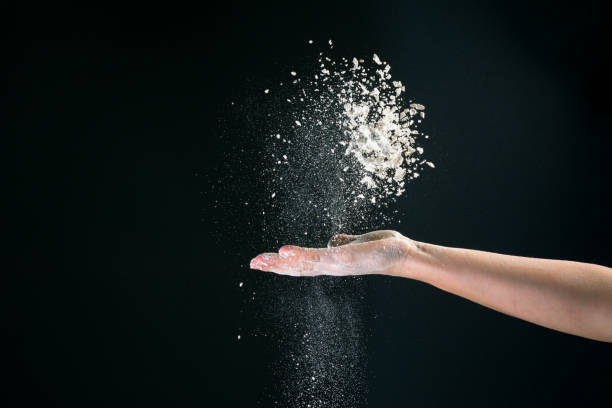 istock On a black background, a woman's hand pours white flour like snow for baking 1251144819
