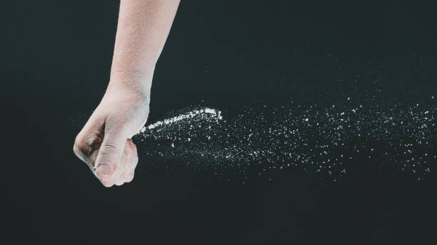 istock On a black background, a woman's hand pours white flour like snow for baking 1251144861