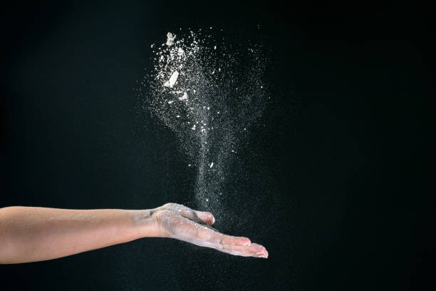 istock On a black background, a woman's hand pours white flour like snow for baking 1251144916