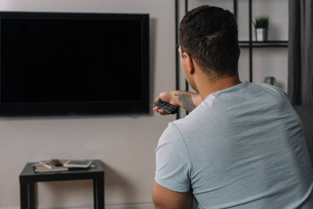 istock back view of mixed race man holding remote controller near flat panel tv with blank screen 1251146711