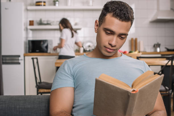 istock selective focus of handsome mixed race man reading book at home 1251146732