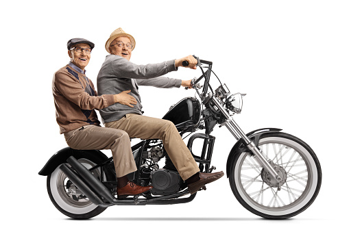 Two elderly men riding a chopper motorbile and looking at the camera isolated on white background