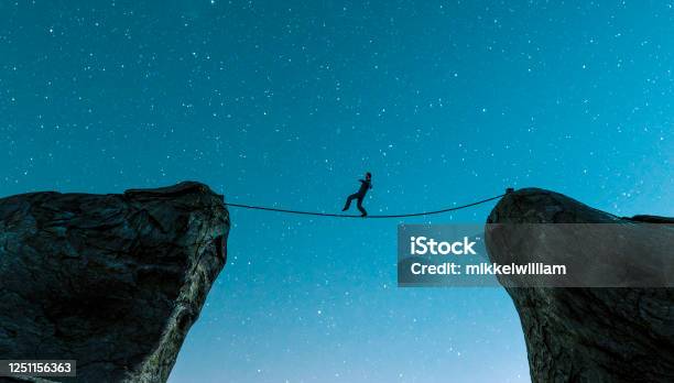Walking On Rope Between Two Cliffs And Keeping The Balance Stock Photo - Download Image Now