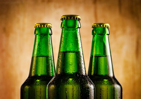 Wet beer bottles on rustic wooden background