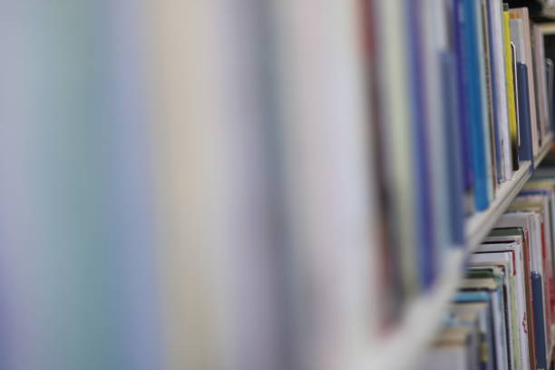 A picture of various coloured books on bookshelves blurred foreground to the left and in focus to the right background