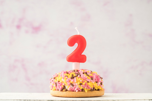 a small coloruful cupcake with number two shaped candle for birthday celebration