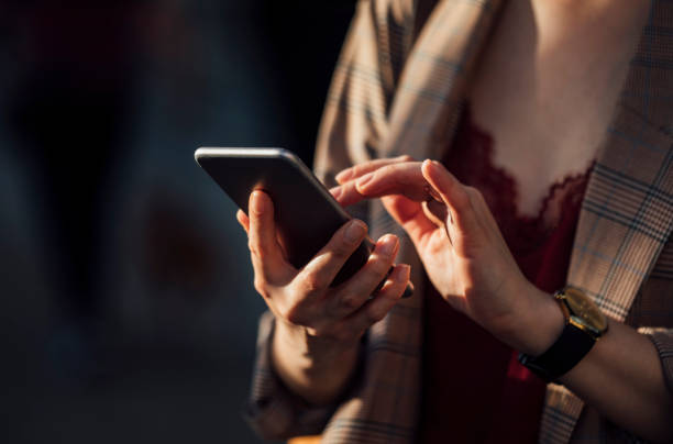istock Online on the Go: Woman Using a Smartphone on the Street 1251158386