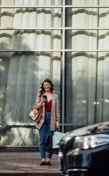 istock Texting and Shopping: a Smiling Woman Using a Smartphone on the Street While Shopping 1251158563