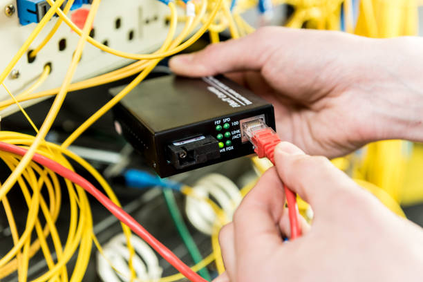 istock Network engineer working in server room. Connecting network cables to switches 1251160024