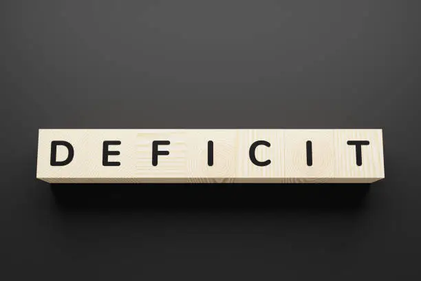 Photo of DEFICIT word on wooden blocks on gray background.