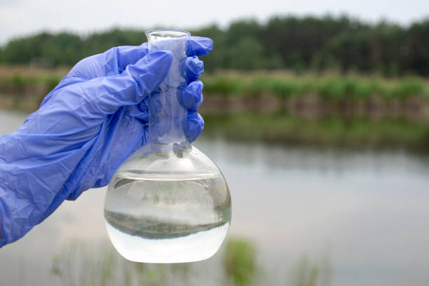 Hand of unrecognizable scientist is experimenting with chemicals in front of white background. Hand is holding laboratory flask with liquid in it.