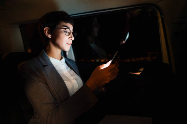 istock Businesswoman using smartphone in a car at night 1251168078