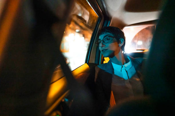 jeune femme d’affaires regardant par la fenêtre de voiture la nuit - monter un animal ou sur un moyen de transport photos et images de collection