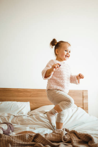 istock Happy little girl having fun in bed while being at home. 1251168433