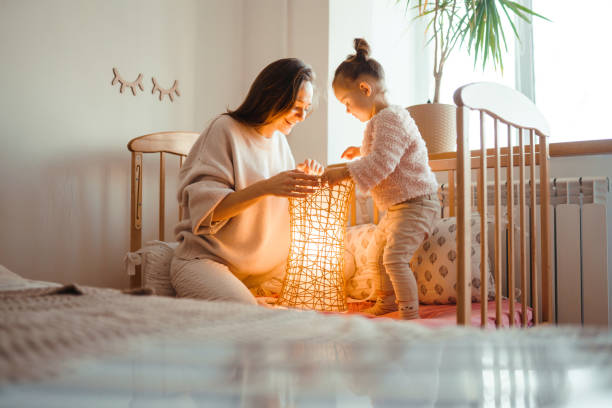Cheerful mother and her little daughter watching at the lamp. stock photo