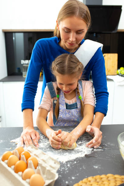 istock Adorable daughter making cookies with mother in kitchen 1251174505