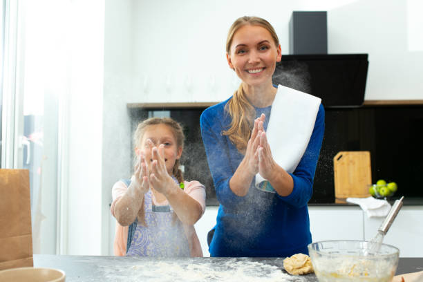 istock Cheerful mother and daughter clapping hands in kitchen 1251174531
