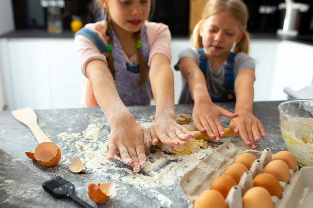 istock Adorable girls rolling dough with rolling pin 1251174555
