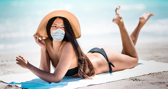 sensual woman resting on the beach with the face mask