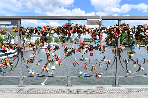 Frankfurt am Main, Germany - June 2020: Bridge railing full of colorful love padlocks at bridge called 'Eiserner Steg' in Frankfurt city on sunny day