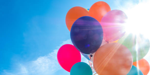 istock Colorful balloons with cloudy sky and sun in background 1251178570