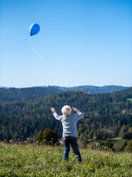 istock Blond boy releasing a balloon into the sky 1251178582