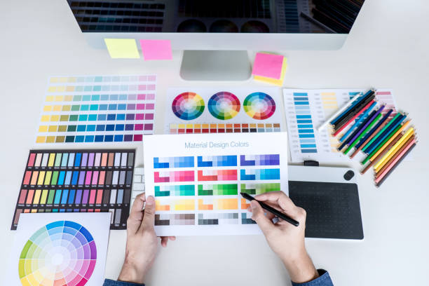Image of male creative graphic designer working on color selection and drawing on graphics tablet at workplace with work tools and accessories, top view workspace stock photo