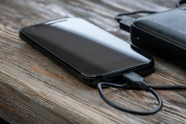istock Smartphone charging with energy bank on wood board 1251188532