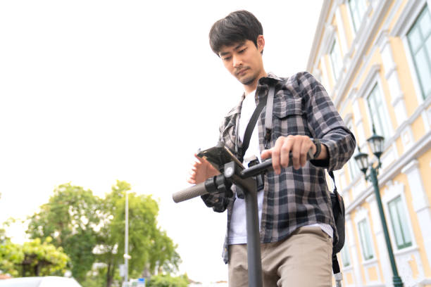 istock male with a backpack on an electric scooter using a mobile phone. 1251189422