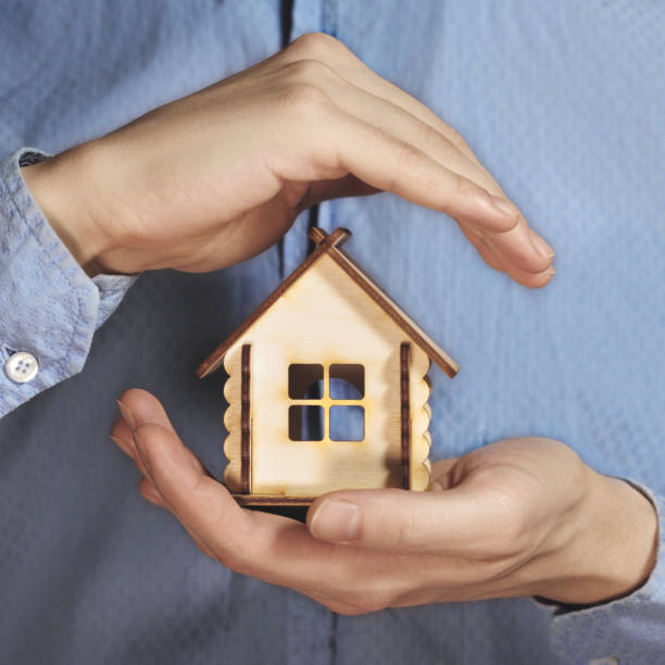 istock Hand holding small wooden house and protecting 1251189552